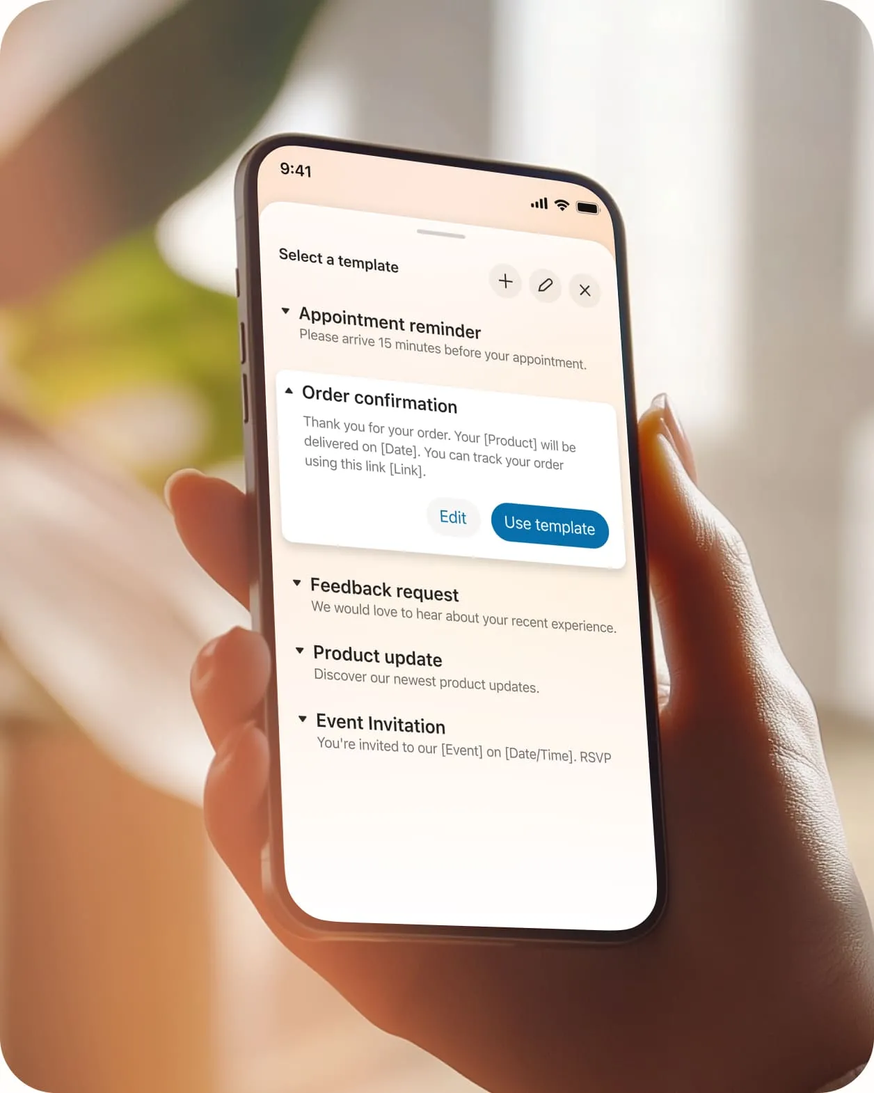 The enhanced business SMS choose a template feature on a mobile phone held in hand