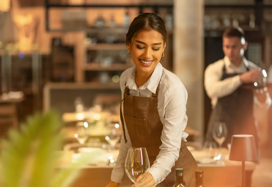 A restaurant server is placing a wine glass on a table