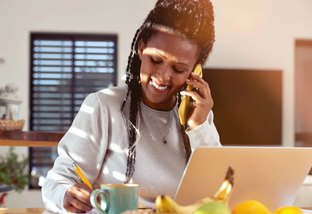 A woman is taking notes while on a mobile call