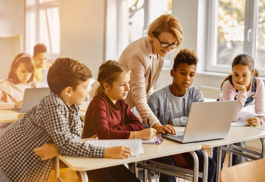 A teacher guides students as they work on homework together 