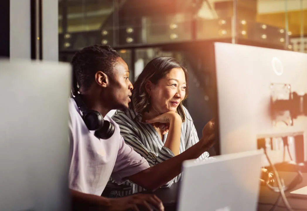 Two women collaborating on a computer in a bright office
