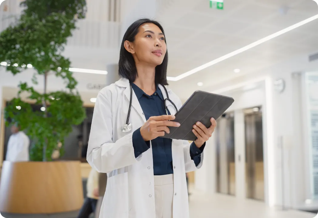 Medical professional looks into the distance while holding a tablet device